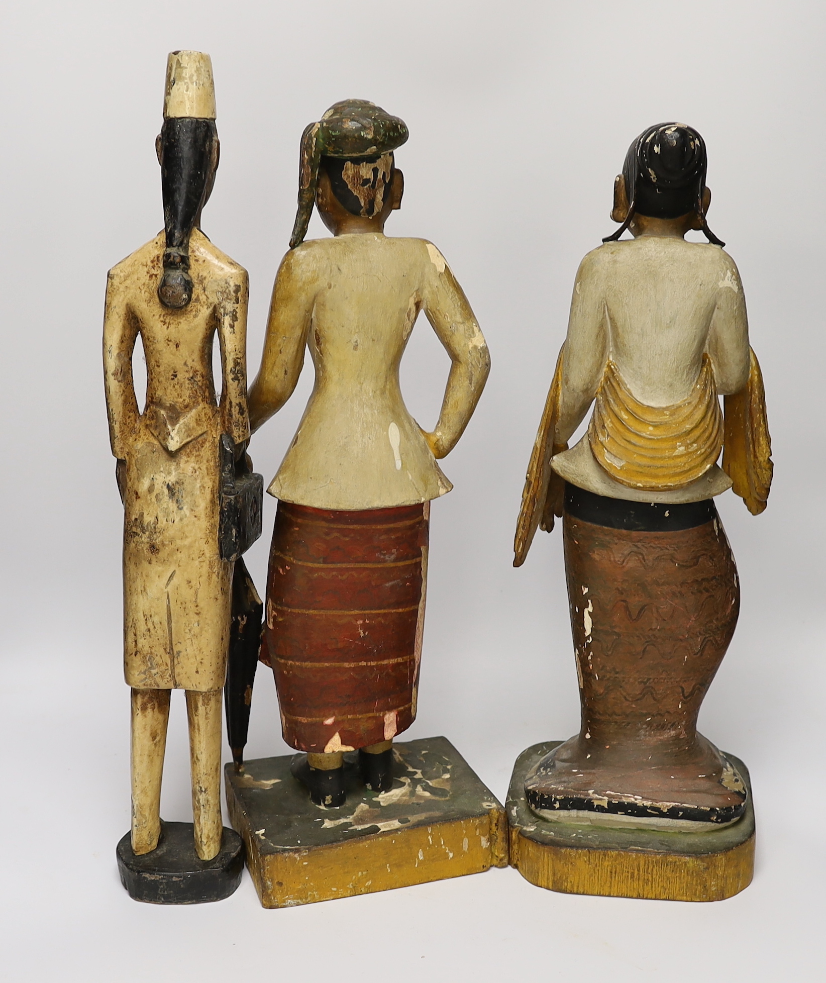 A pair of Indonesian painted carvings, two females and another, largest 44cm high